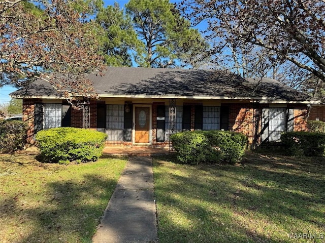 view of front of home featuring brick siding, a front yard, and a shingled roof