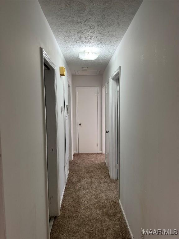 corridor with baseboards, carpet floors, and a textured ceiling