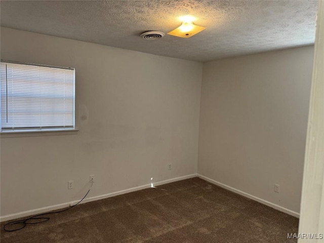 empty room with baseboards, visible vents, dark colored carpet, and a textured ceiling