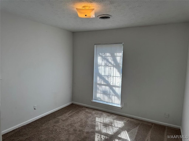 empty room with visible vents, a textured ceiling, baseboards, and carpet floors