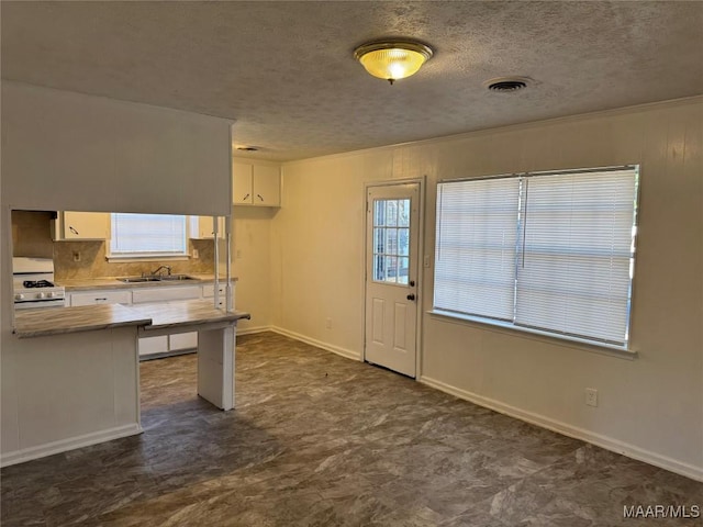 kitchen with visible vents, light countertops, white range with gas cooktop, white cabinets, and a sink