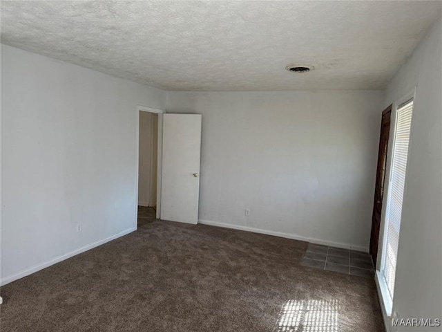 carpeted empty room with visible vents, a textured ceiling, and a healthy amount of sunlight