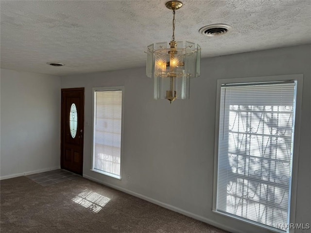 carpeted foyer with visible vents, baseboards, and a textured ceiling