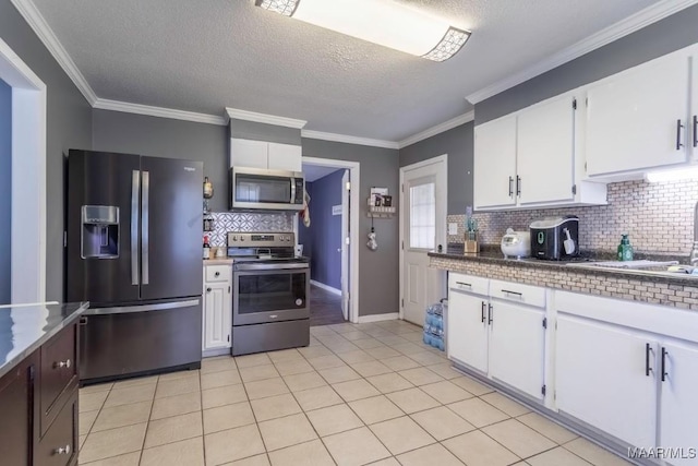 kitchen featuring light tile patterned floors, white cabinets, stainless steel appliances, and crown molding