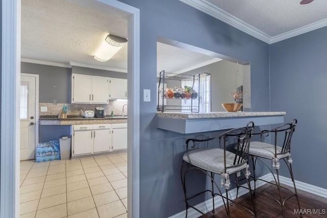 kitchen featuring light tile patterned floors, decorative backsplash, white cabinets, and crown molding