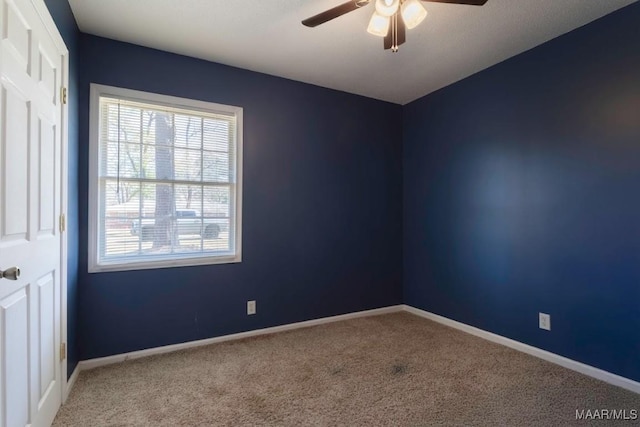 carpeted spare room featuring baseboards and ceiling fan