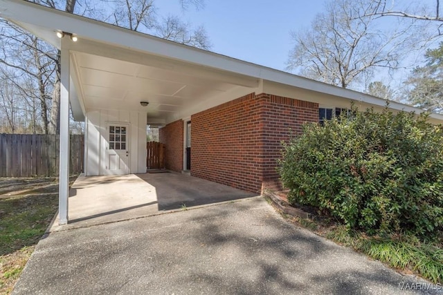 exterior space featuring a carport, fence, and driveway