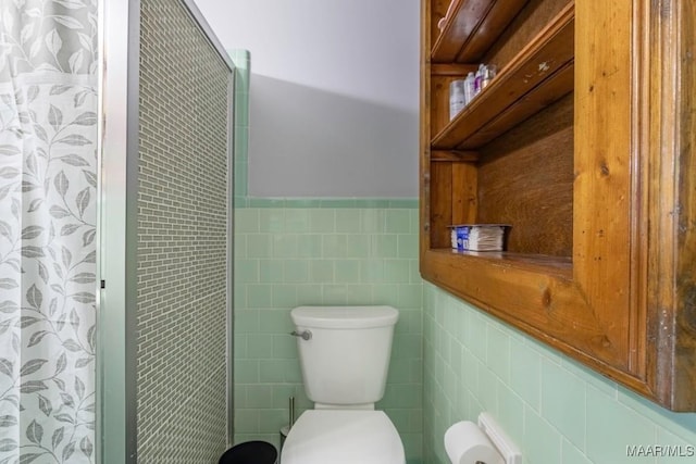 bathroom featuring a wainscoted wall, toilet, tile walls, and a shower with curtain