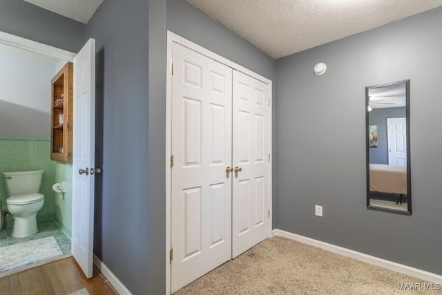 bedroom featuring a closet, a textured ceiling, tile walls, and ensuite bathroom