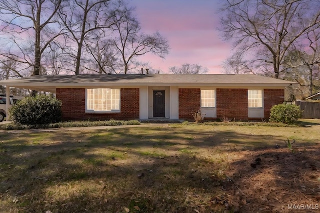 ranch-style house featuring a yard, brick siding, and fence