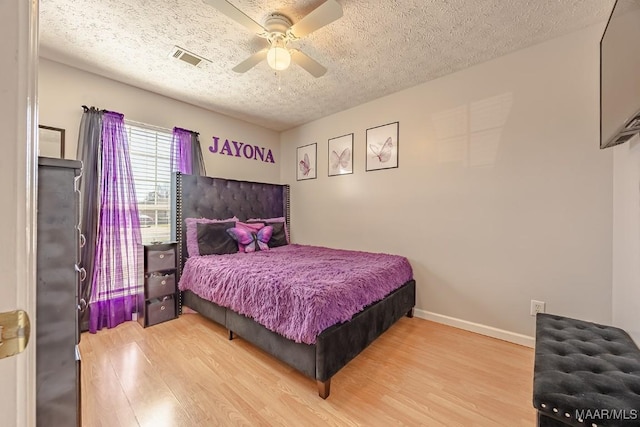 bedroom with visible vents, baseboards, a textured ceiling, and wood finished floors