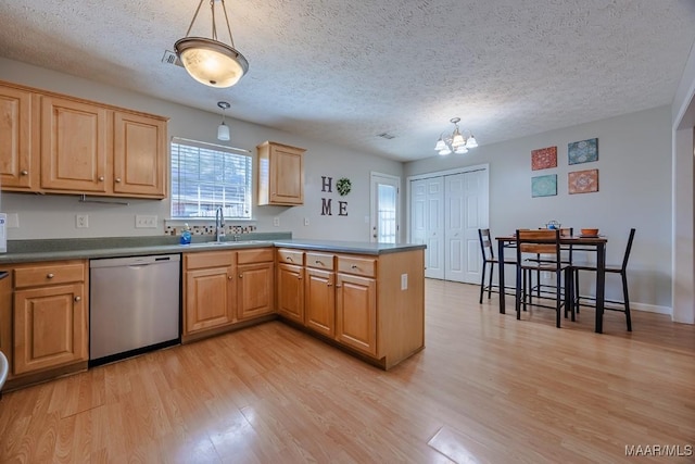 kitchen featuring light wood-type flooring, a sink, stainless steel dishwasher, a peninsula, and hanging light fixtures