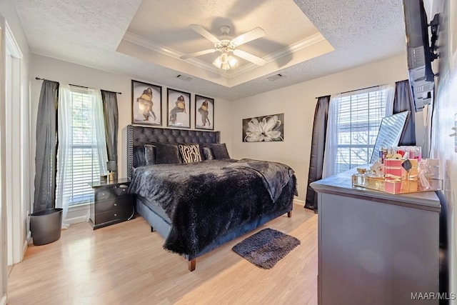 bedroom featuring a raised ceiling, light wood-type flooring, and ornamental molding