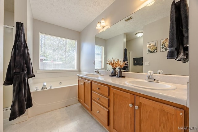 full bath with visible vents, double vanity, a sink, a textured ceiling, and a garden tub