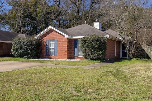 single story home with brick siding, a chimney, and a front yard