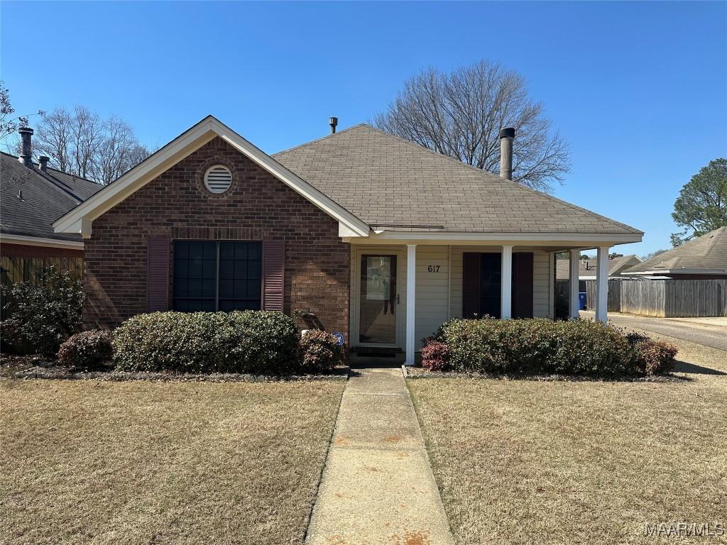 single story home featuring brick siding, a front lawn, and roof with shingles