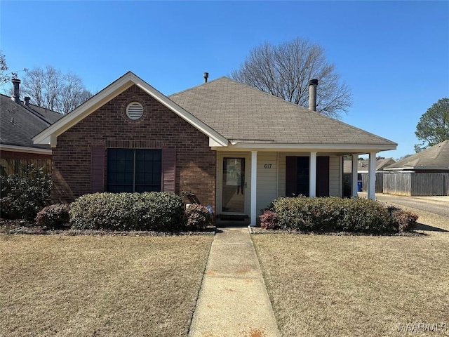 single story home featuring brick siding, a front lawn, and roof with shingles