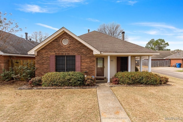 ranch-style house with brick siding, roof with shingles, a front yard, and fence