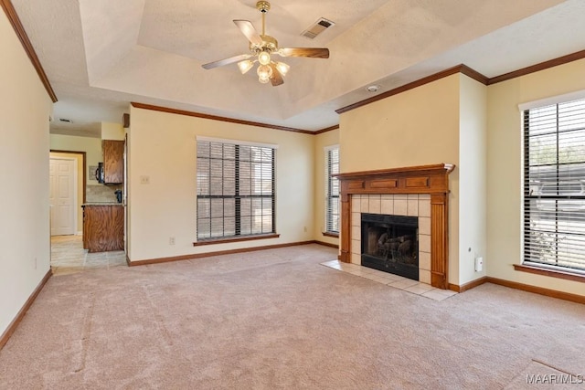 unfurnished living room featuring a wealth of natural light, visible vents, light colored carpet, and a tray ceiling