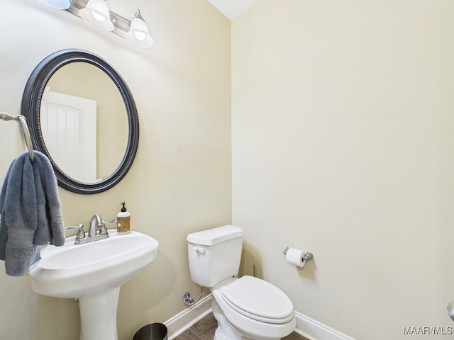 bathroom with baseboards, toilet, and tile patterned flooring