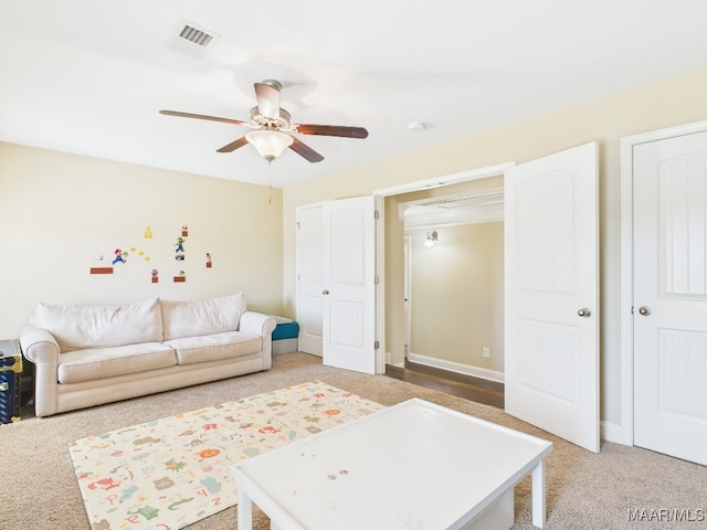 living room with visible vents, light carpet, baseboards, and a ceiling fan