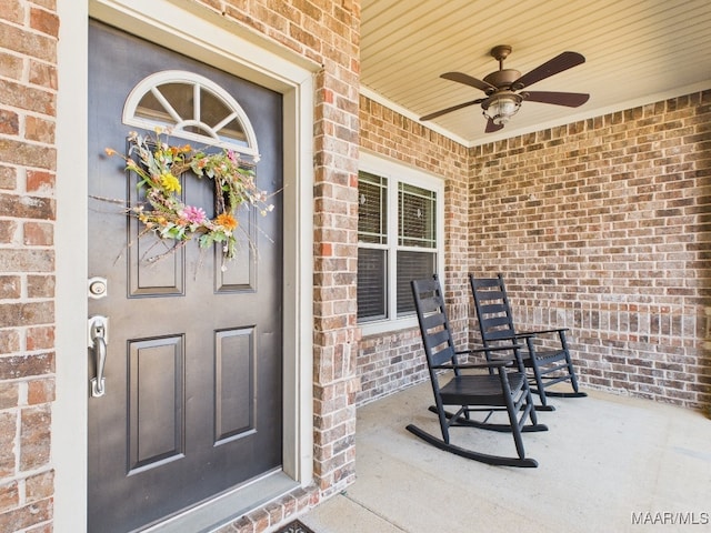 property entrance featuring brick siding, covered porch, and a ceiling fan