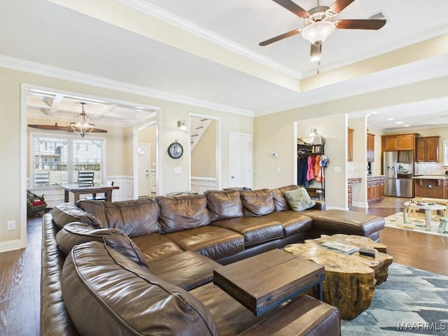 living area featuring wood finished floors, visible vents, coffered ceiling, ornamental molding, and ceiling fan with notable chandelier