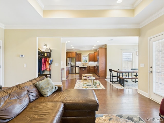 living area featuring dark wood-style floors, baseboards, a tray ceiling, recessed lighting, and ornamental molding