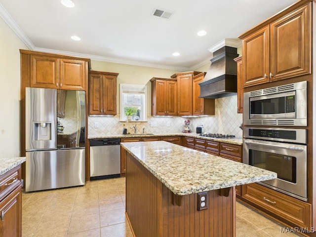 kitchen with light stone counters, visible vents, custom exhaust hood, a sink, and stainless steel appliances