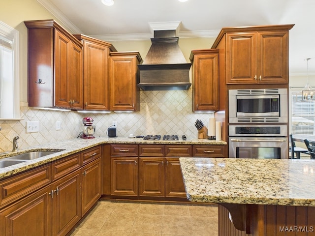 kitchen with ornamental molding, tasteful backsplash, appliances with stainless steel finishes, light stone countertops, and custom exhaust hood