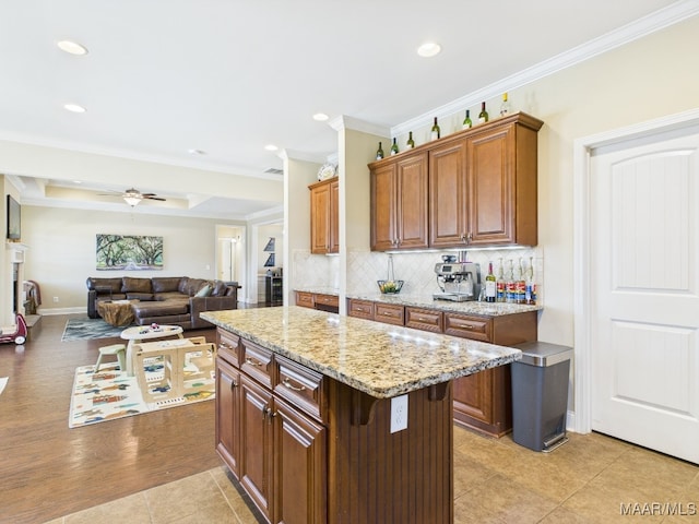 kitchen featuring crown molding, light stone counters, open floor plan, and backsplash