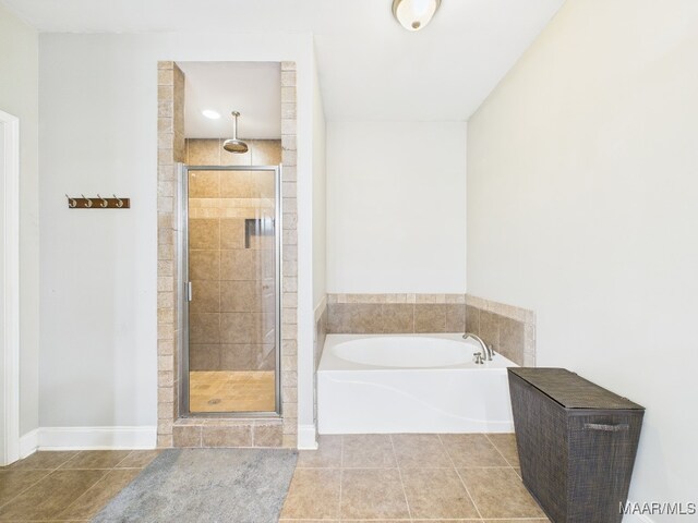 full bathroom featuring tile patterned flooring, a bath, and a stall shower