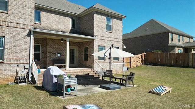 rear view of house with brick siding, a patio area, a lawn, and fence