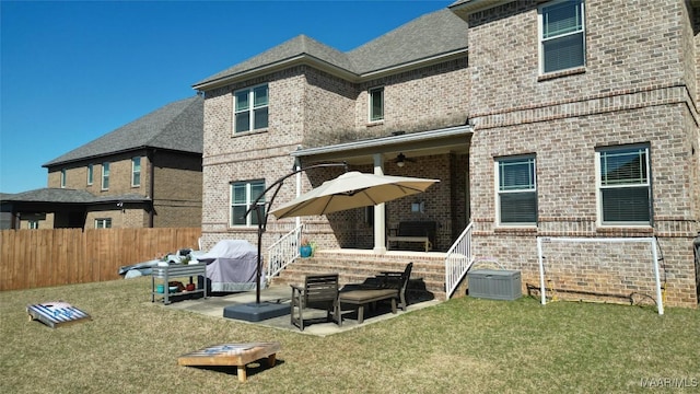 rear view of house featuring a ceiling fan, a patio, fence, a yard, and brick siding