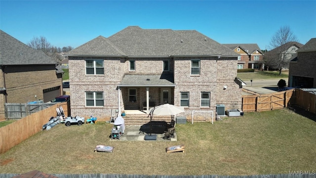 rear view of property featuring a patio, a yard, a fenced backyard, central air condition unit, and brick siding