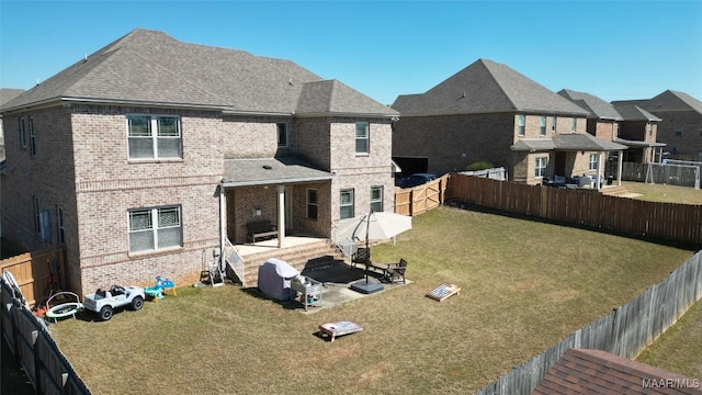 back of house with a patio, a fenced backyard, a yard, a shingled roof, and brick siding