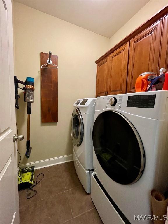 washroom with tile patterned floors, cabinet space, independent washer and dryer, and baseboards