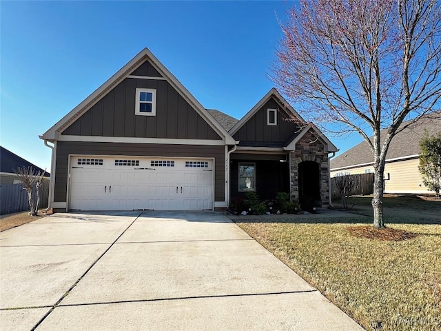 craftsman house featuring driveway, stone siding, fence, board and batten siding, and a front yard