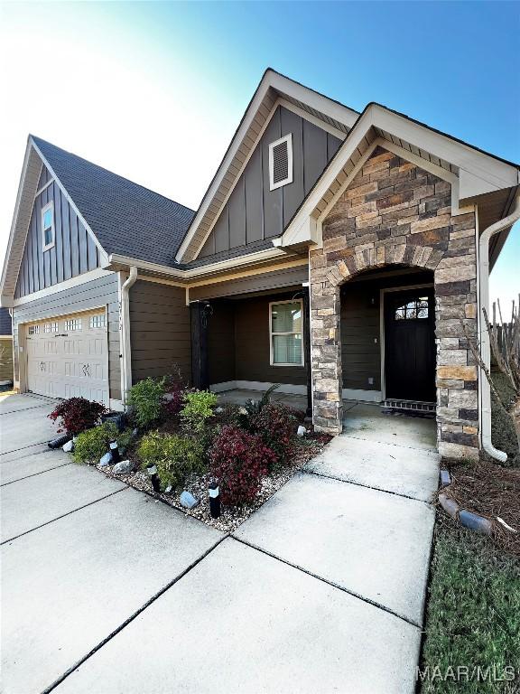 view of front of home with a garage, stone siding, board and batten siding, and concrete driveway