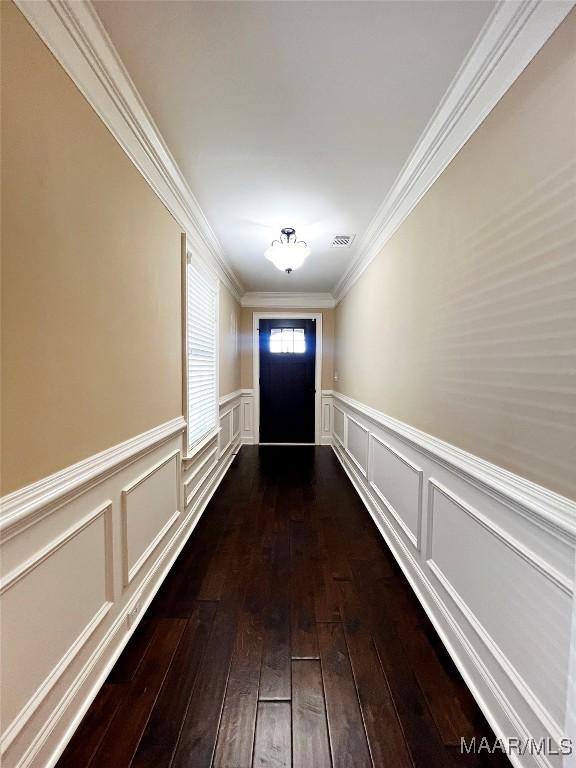 entryway with visible vents, a wainscoted wall, dark wood-style floors, and ornamental molding