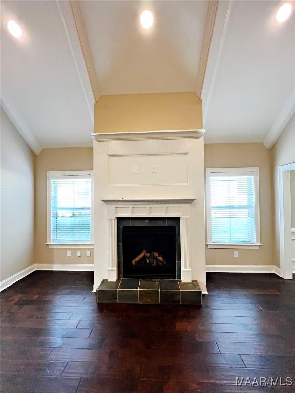 unfurnished living room featuring hardwood / wood-style floors, a tiled fireplace, and vaulted ceiling