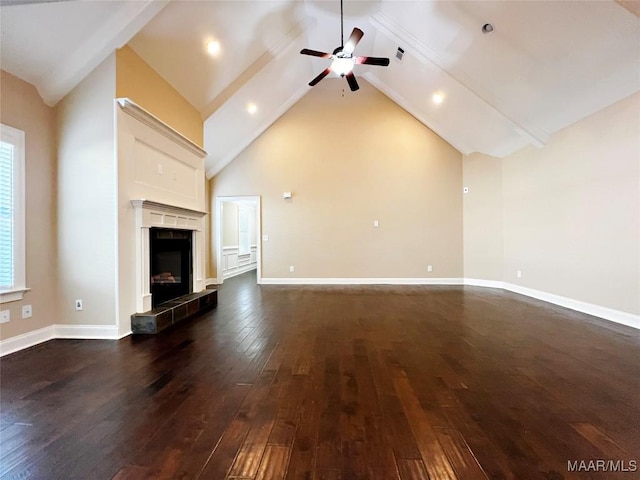 unfurnished living room featuring dark wood-type flooring, baseboards, a tiled fireplace, high vaulted ceiling, and a ceiling fan