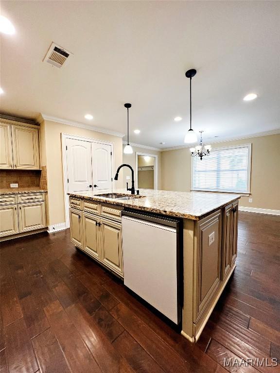 kitchen featuring dishwashing machine, visible vents, an island with sink, a sink, and cream cabinetry