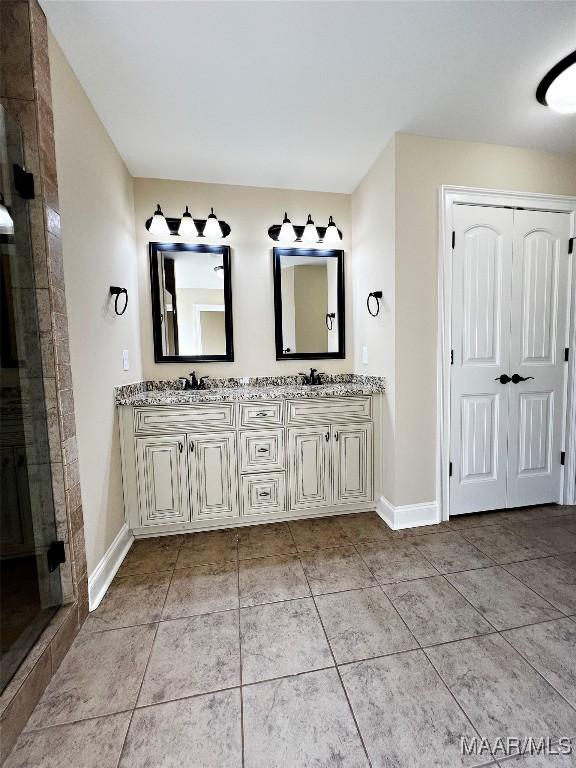 bathroom featuring double vanity, tile patterned floors, baseboards, and a sink