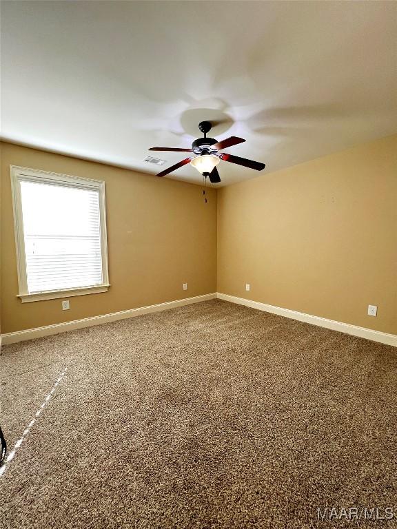 carpeted empty room featuring visible vents, ceiling fan, and baseboards