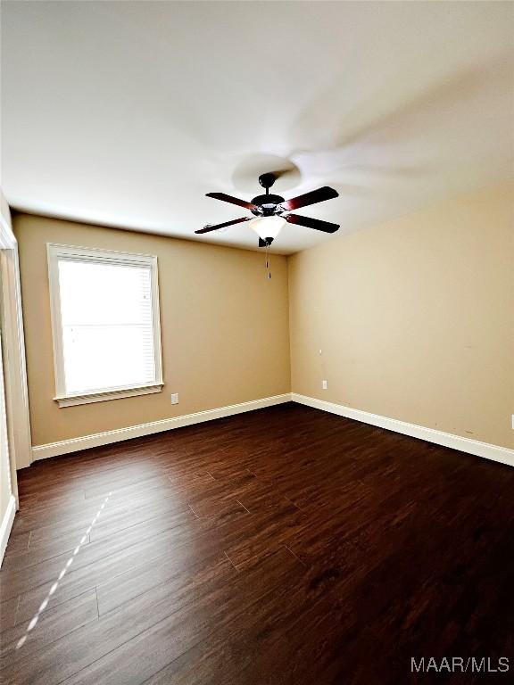 spare room featuring ceiling fan, baseboards, and dark wood finished floors