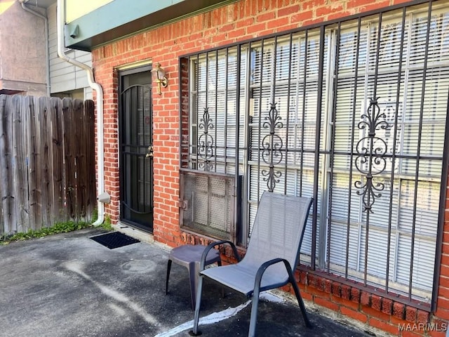 property entrance with brick siding and fence