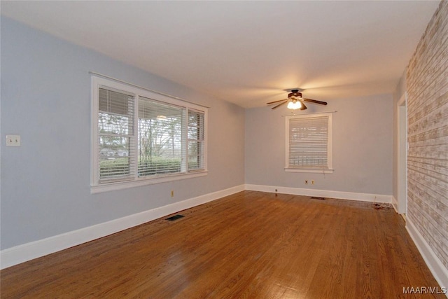 spare room featuring visible vents, a ceiling fan, baseboards, and wood finished floors