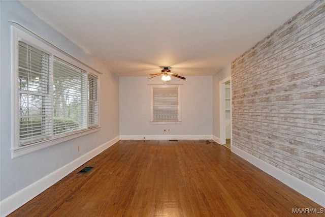 spare room featuring a ceiling fan, wood finished floors, and baseboards