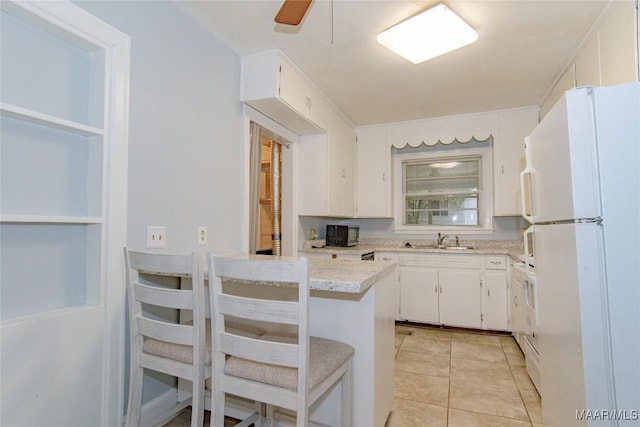 kitchen with light tile patterned floors, freestanding refrigerator, white cabinetry, a ceiling fan, and a sink